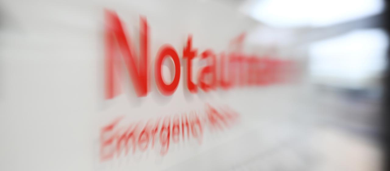 Auf einem Schild in einem Krankenhaus ist das Wort Notaufnahme verschwommen zu sehen