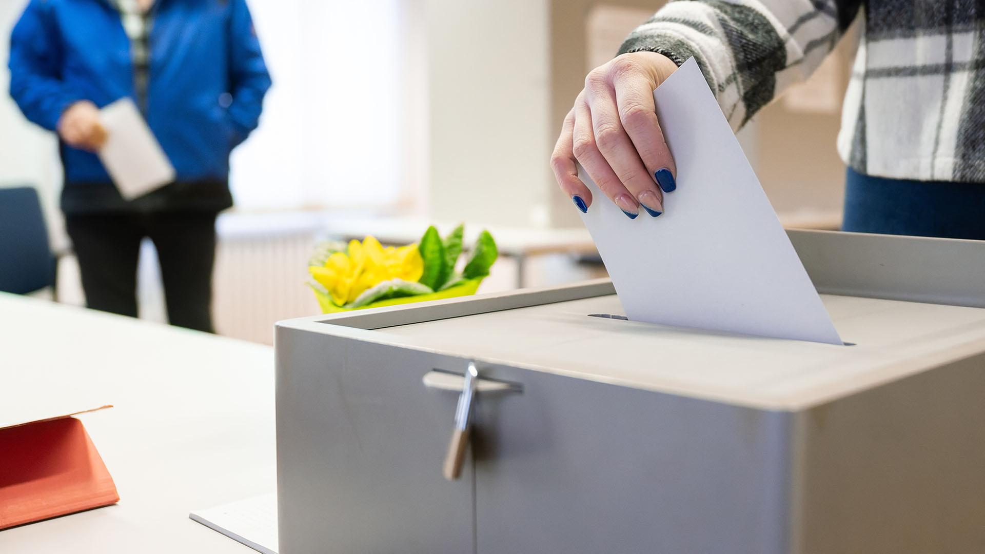 Eine Frau steckt ihren Stimmzettel zur Landtagswahl in Baden-Württemberg in eine Wahlurne. | picture alliance/dpa