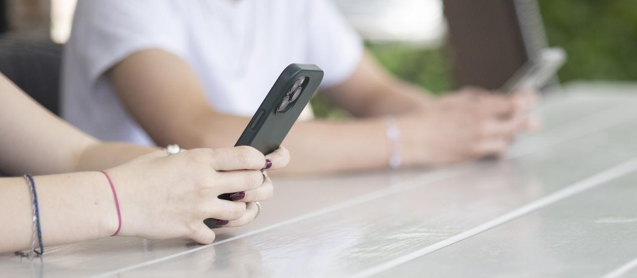 Jugendliche spielen auf ihren Smartphones.
