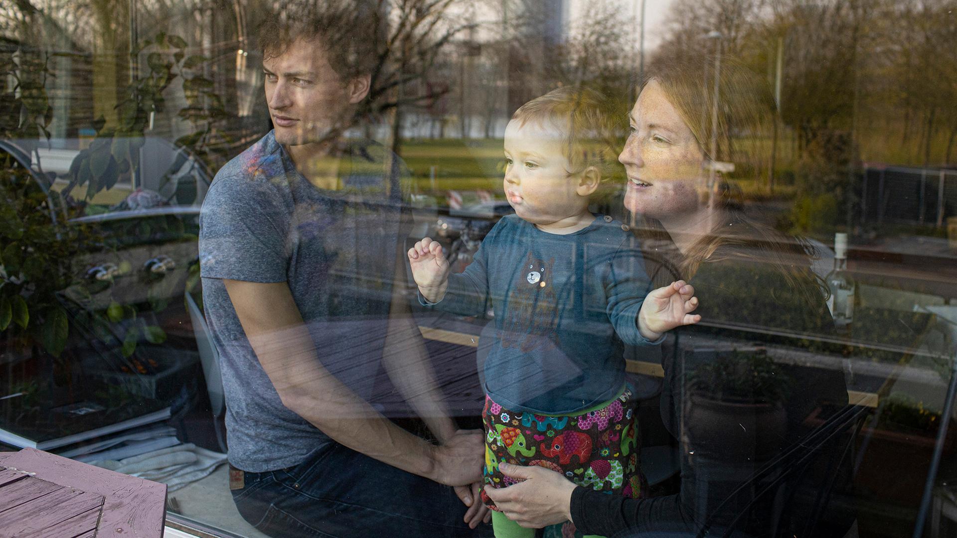 Eine Familie schaut durch ein Fenster nach draußen. | picture alliance / photothek