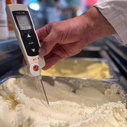 Mit einem Thermometer wird die Temperatur von Speiseeis überprüft.