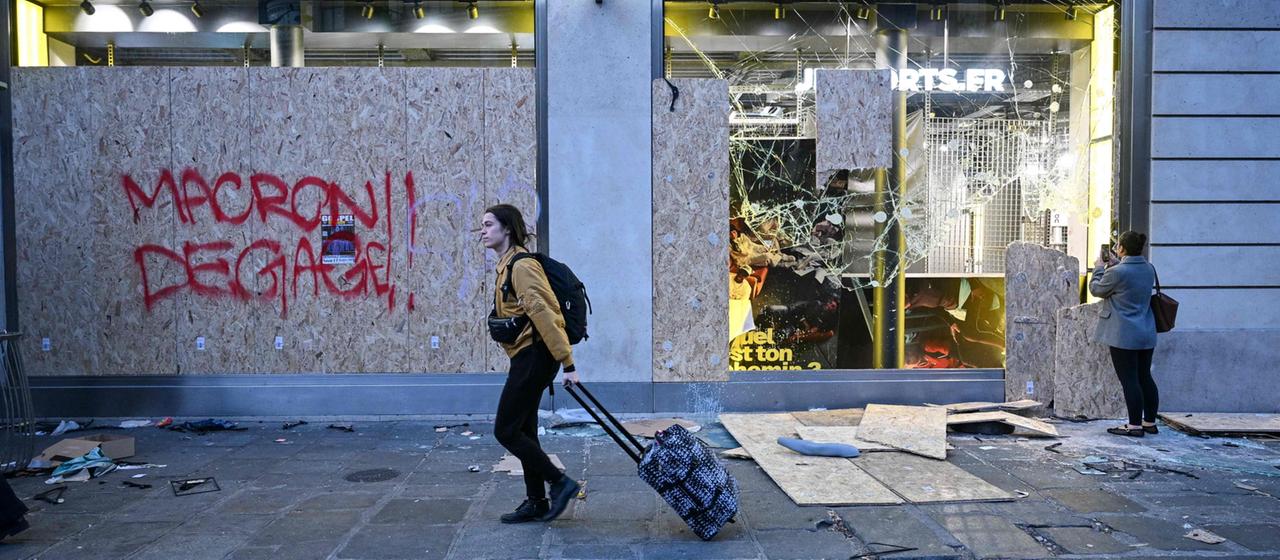 Eine Fußgängerin geht an einem beschädigten Geschäft in Paris vorbei.