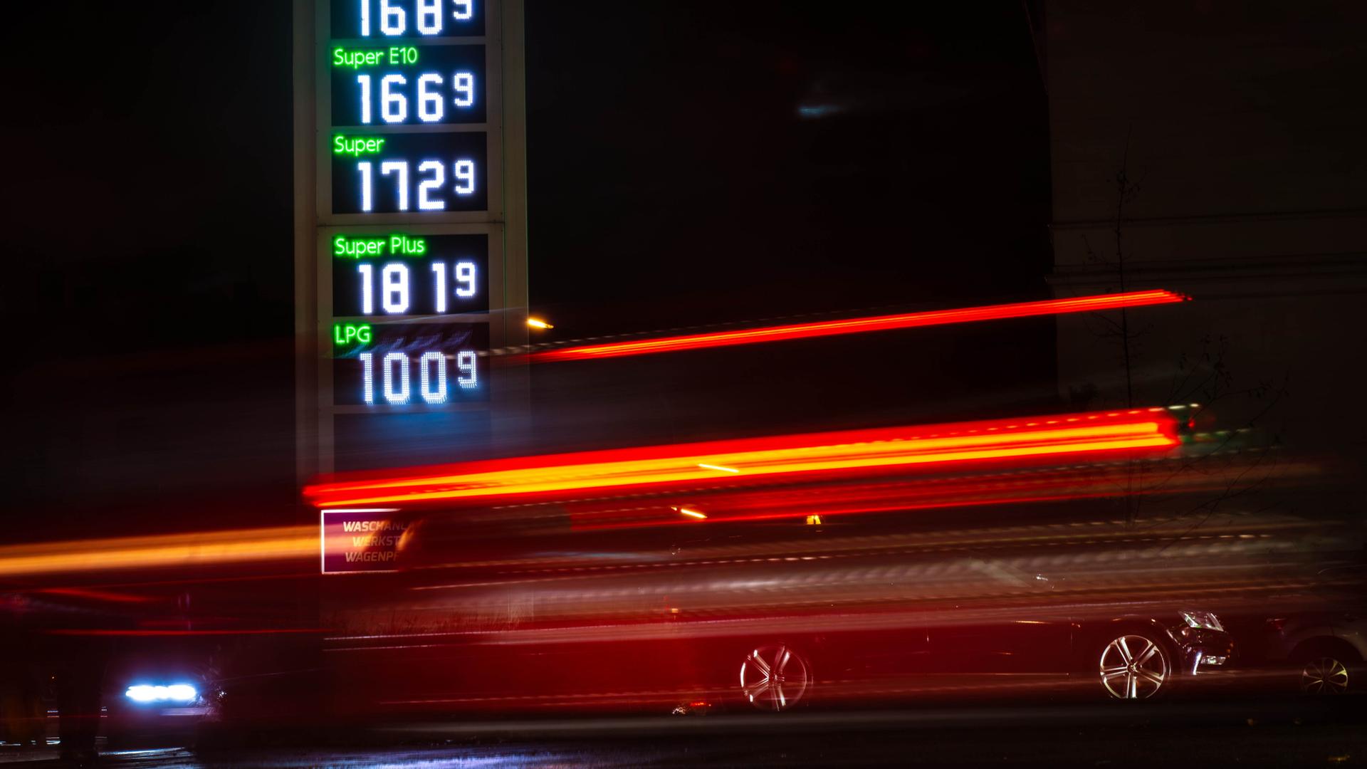 Autos fahren im Dunkeln an einer Tankstelle vorbei, die Kraftstoffpreise anzeigt (Archiv) | dpa