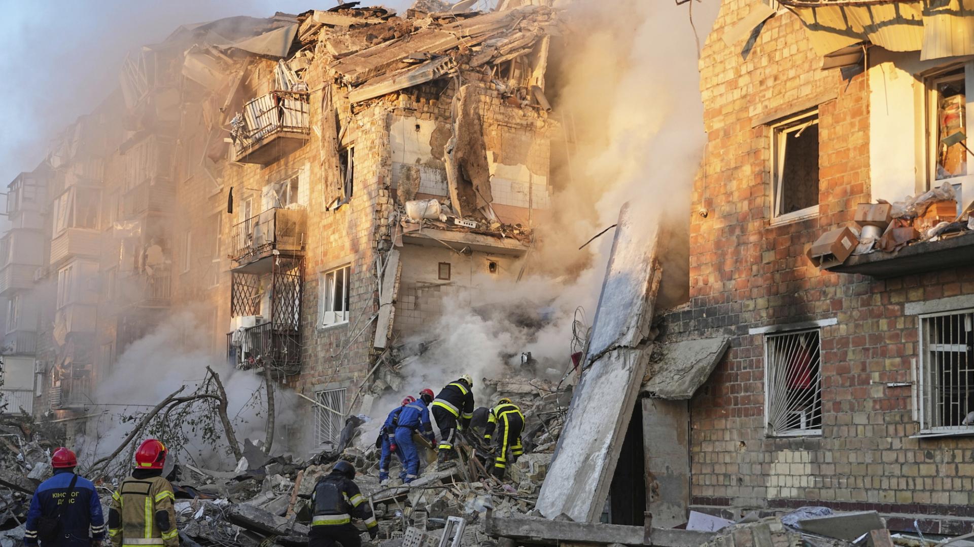 Feuerwehrleute arbeiten an einem brennenden Gebäude nach einem Angriff in Kiew. | dpa