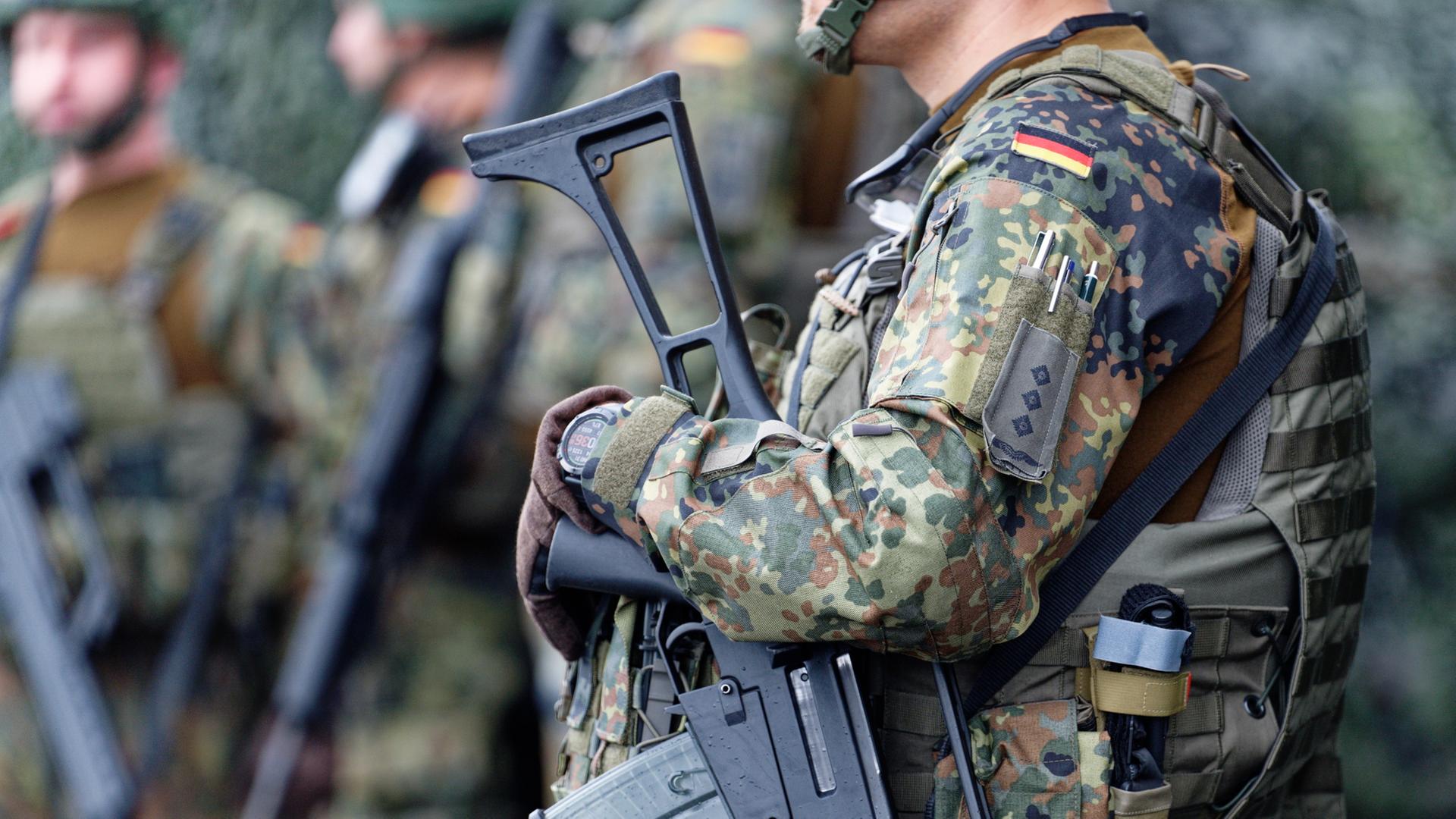 Bundeswehrsoldaten im Kampfanzug und mit Gewehr stehen zusammen  | dpa