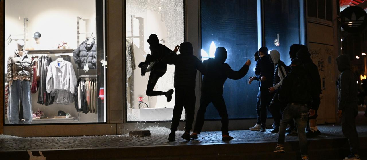 Jugendliche zerschlagen bei Zusammenstößen zwischen Demonstranten und der Polizei in Paris eine Schaufensterscheibe.