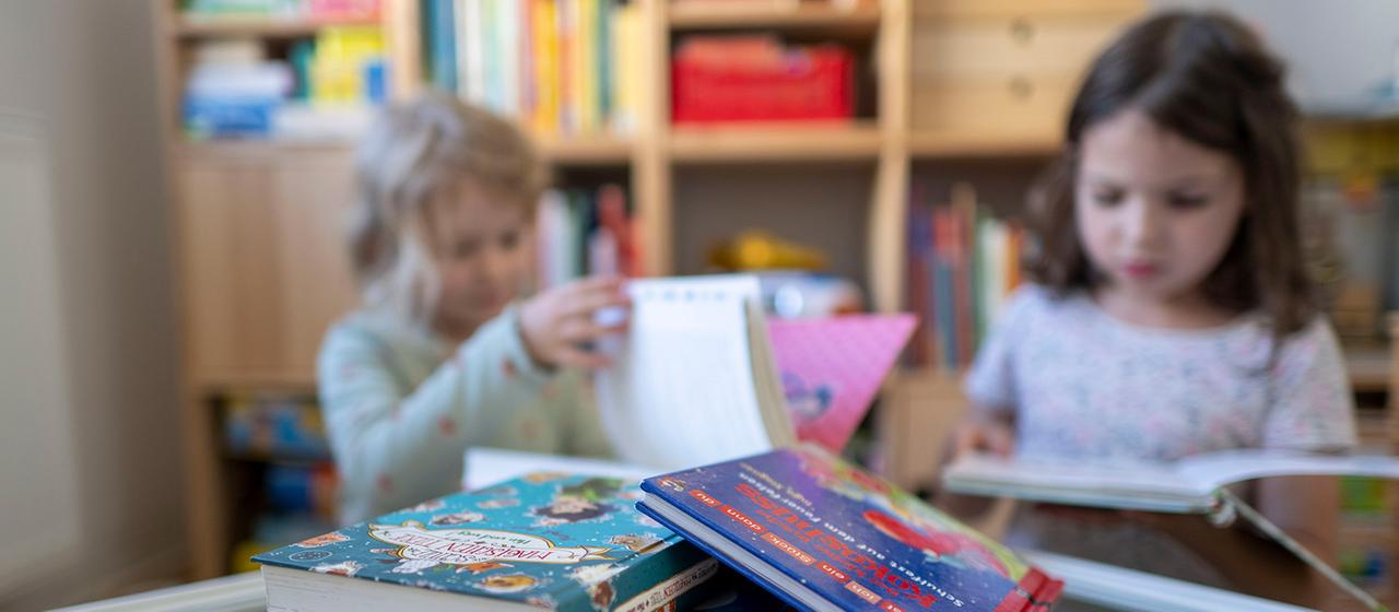 Zwei Kinder schauen sich Bücher an.