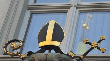 Das Kreuz des Doms spiegelt sich am Donnerstag in Augsburg in einem Fenster am Bischofspalais.