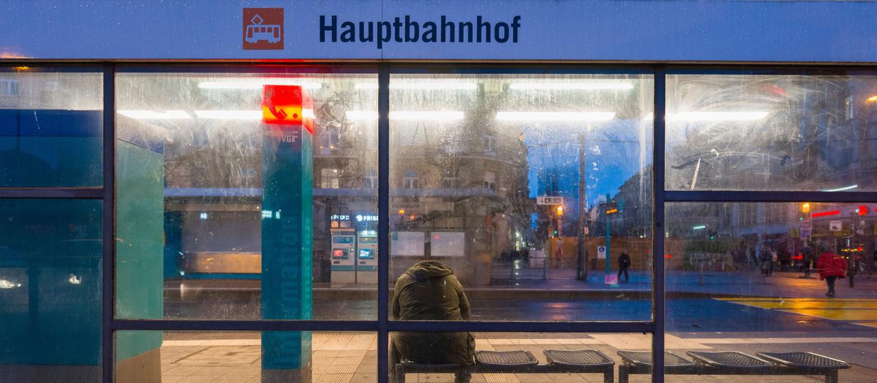 Ein Mann wartet an der Straßenbahnhaltestelle Hauptbahnhof in Frankfurt/Main auf ein öffentliches Verkehrsmittel.