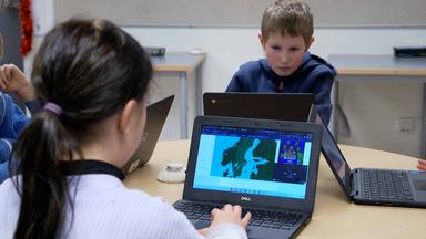 Kinder sitzen in einer schwedischen Schule vor Laptops