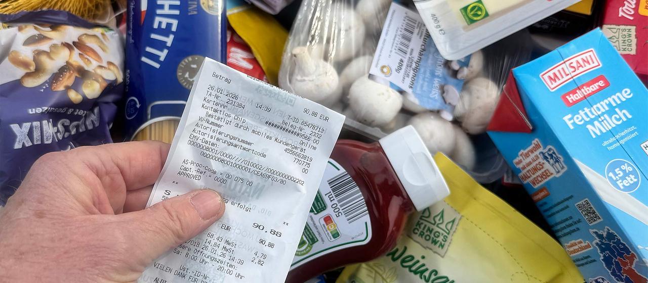 Blick auf einen Kassenbon und einen gefüllten Warenkorb.