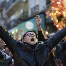 Ein Mann steht in Paris mit erhobenen Armen in einer Menge, die gegen die Rentenreform protestiert