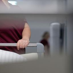 Eine Krankenpflegerin schiebt ein Krankenbett durch den Gang einer Station eines Krankenhauses.