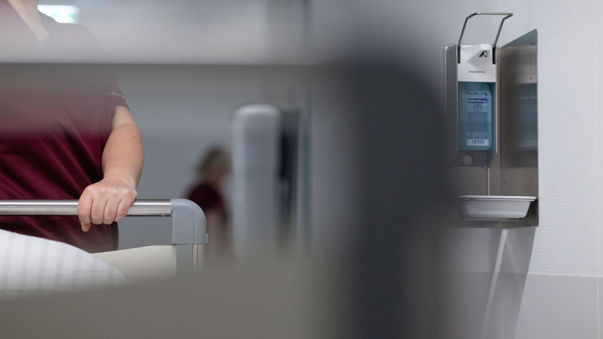 Eine Krankenpflegerin schiebt ein Krankenbett durch den Gang einer Station eines Krankenhauses. | picture alliance/dpa