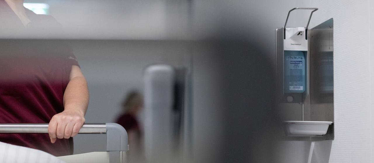 Eine Krankenpflegerin schiebt ein Krankenbett durch den Gang einer Station eines Krankenhauses.