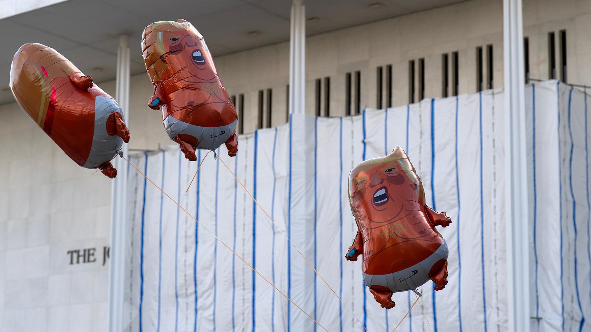 Ballons die Donald Trump Ã¤hneln schweben vor dem John F. Kennedy Center for the Performing Arts. | Jose Luis Magana/AP/dpa
