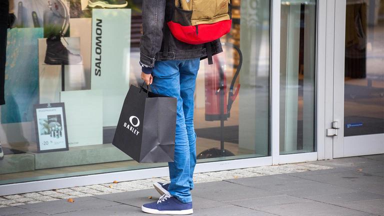 Kunde mit Einkaufstüte vor einem Schaufenster.