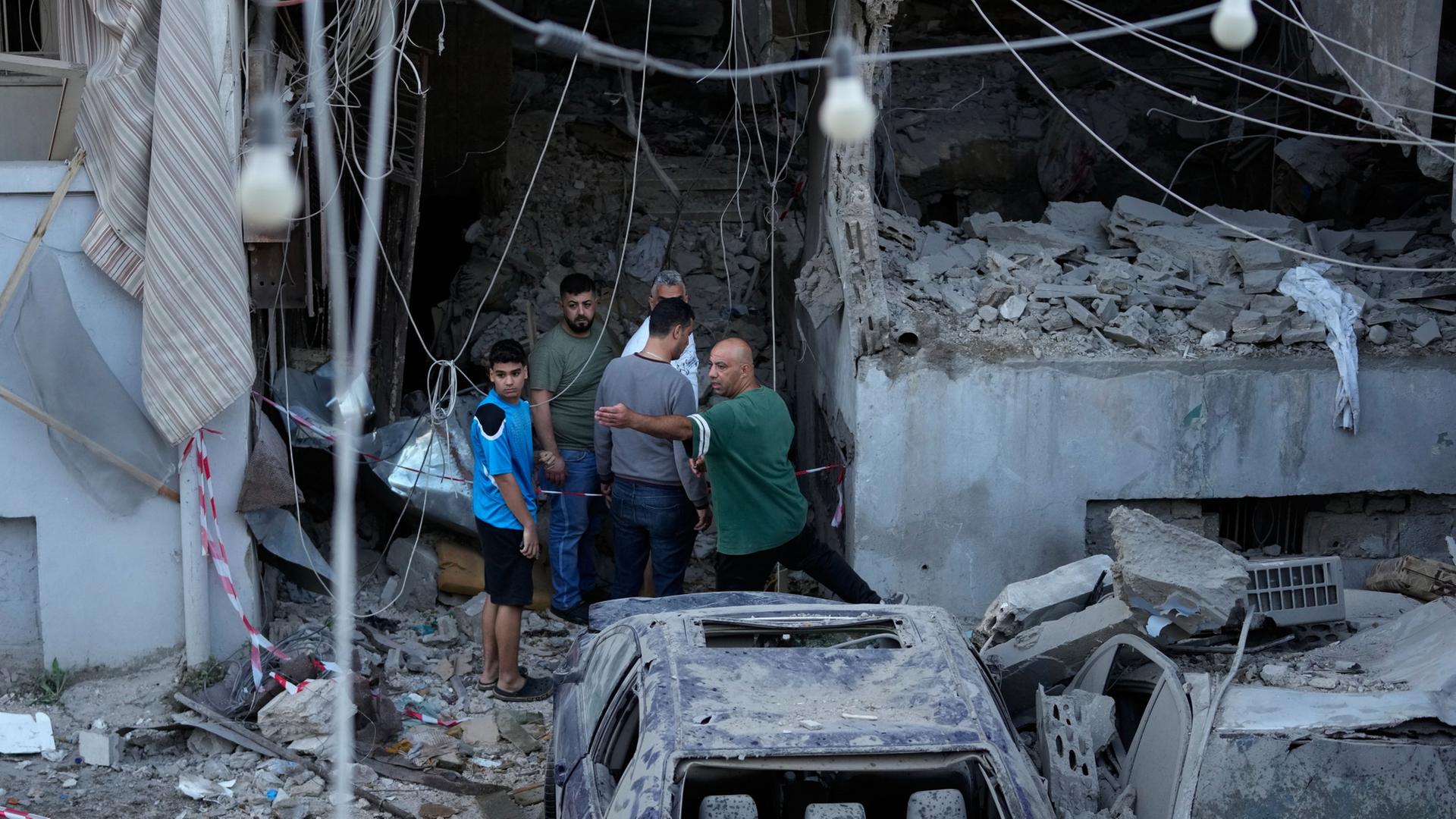 Menschen versammeln sich vor einer zerstörten Wohnung in der libanesischen Hafenstadt Sidon. | Mohammed Zaatari/AP/dpa