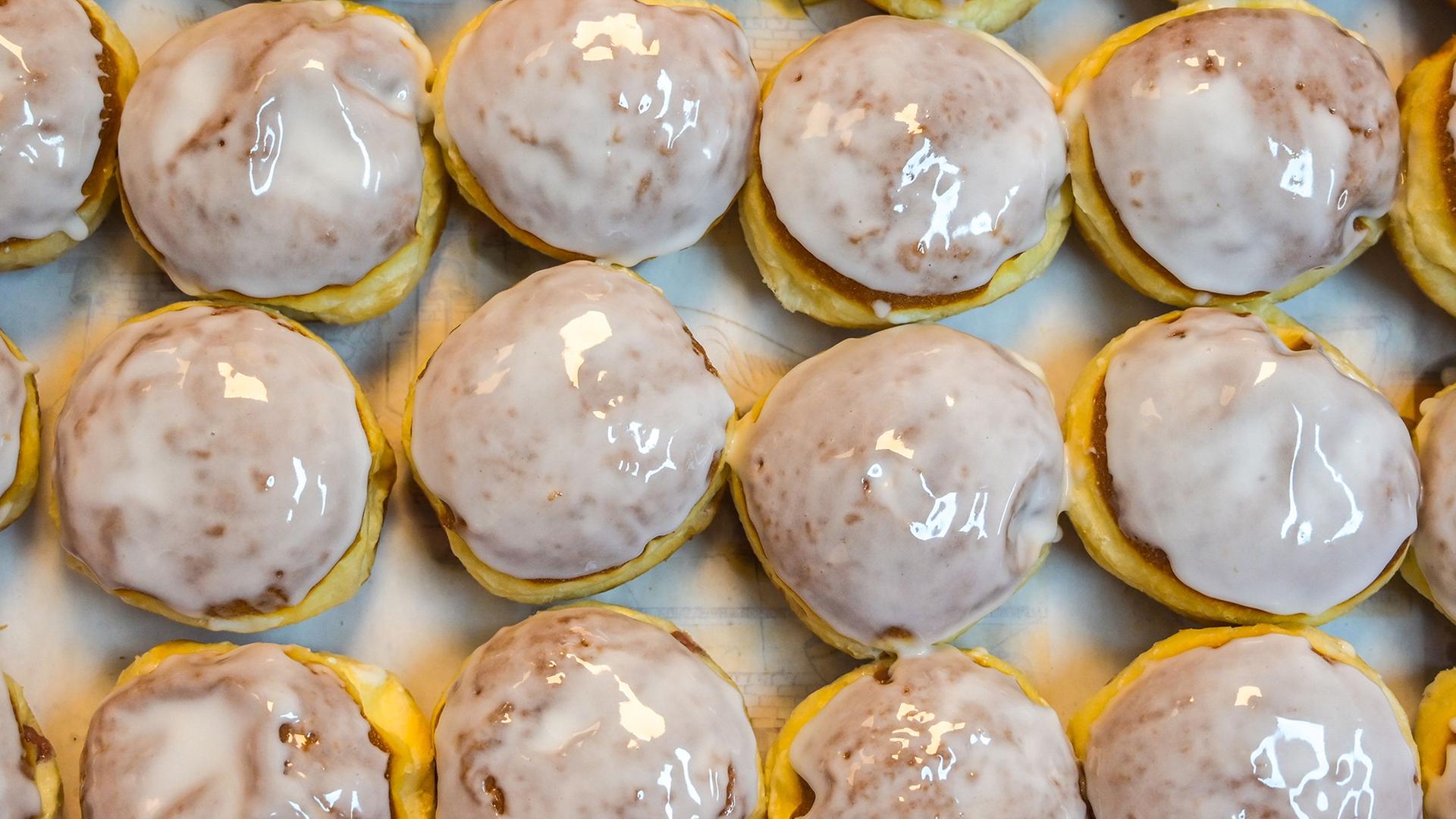 Frisch glasierte Pfannkuchen liegen dicht an dicht in einer Transportkiste. | Heiko Rebsch/dpa