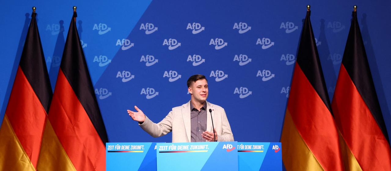 Jean-Pascal Hohm auf einer Bühne mit Deutschlandflaggen und AfD-Logos