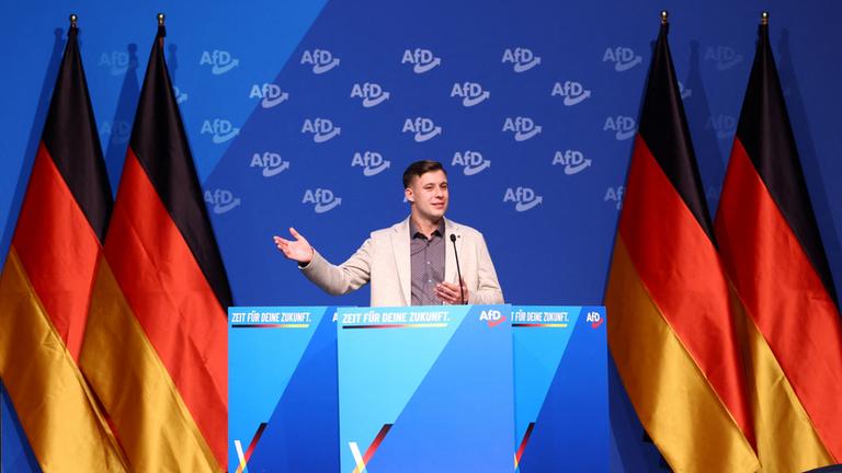 Jean-Pascal Hohm auf einer Bühne mit Deutschlandflaggen und AfD-Logos
