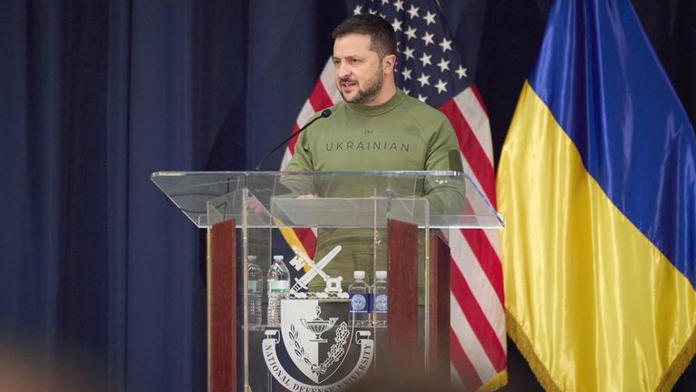 Wolodomyr Selenskyj spricht vor den Flaggen der USA und der Ukraine.