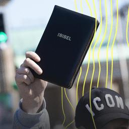 Ein Mann hält bei einer Demonstration vor dem Brandenburger Tor eine Bibel in der Hand.