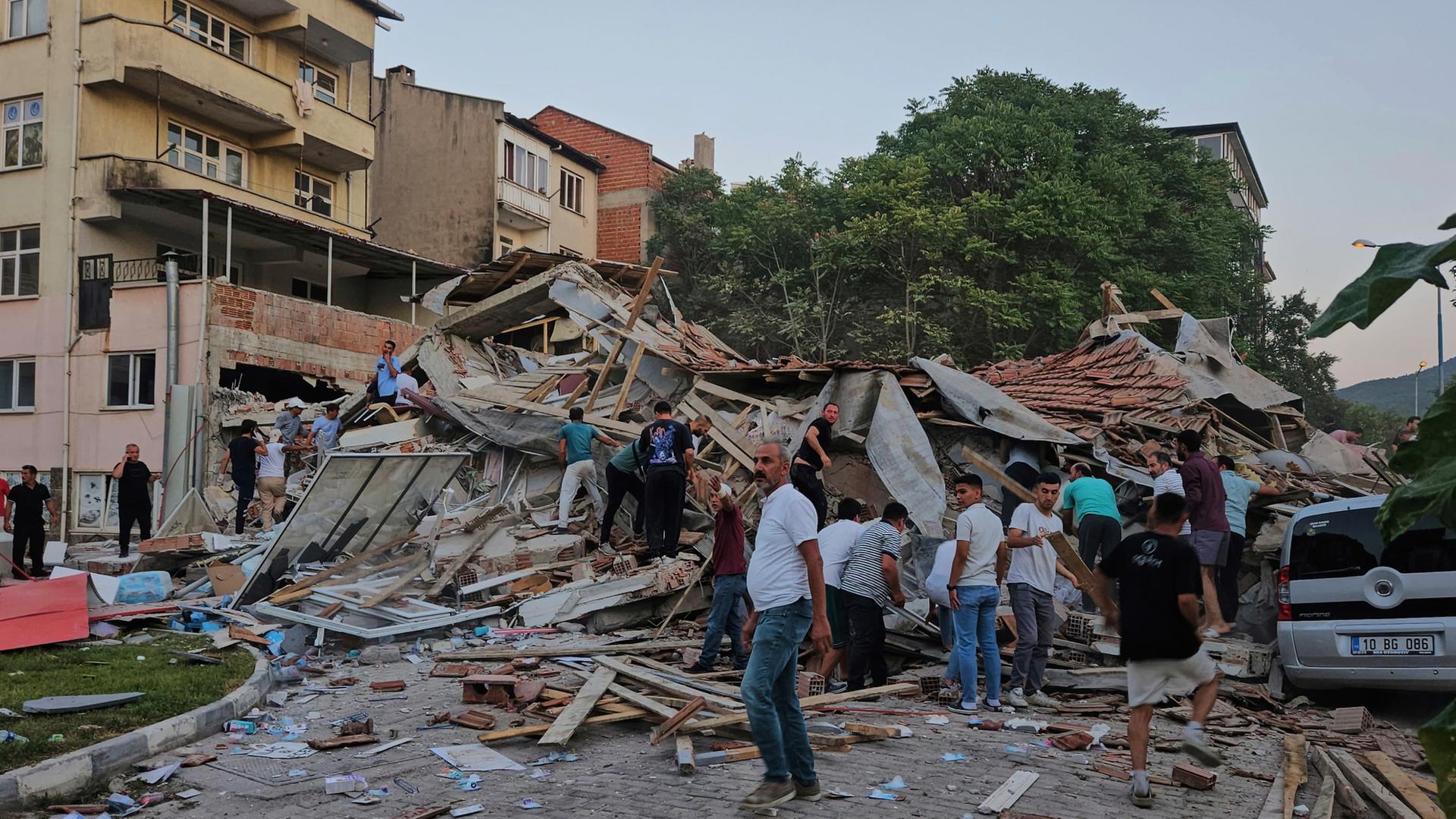 Menschen vor eingestürztem Haus in der Westtürkei | dpa
