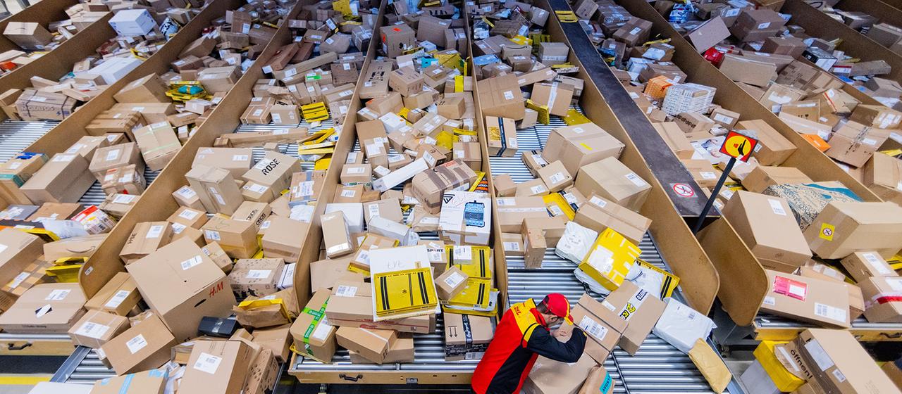 Ein Paketzusteller sortiert und räumt Pakete in ein Zustellfahrzeug.