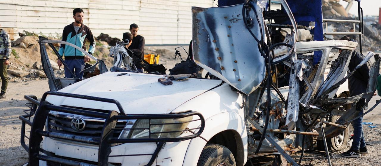 Menschen begutachten den Ort eines israelischen Luftangriffes auf ein Polizeiauto im Gazastreifen