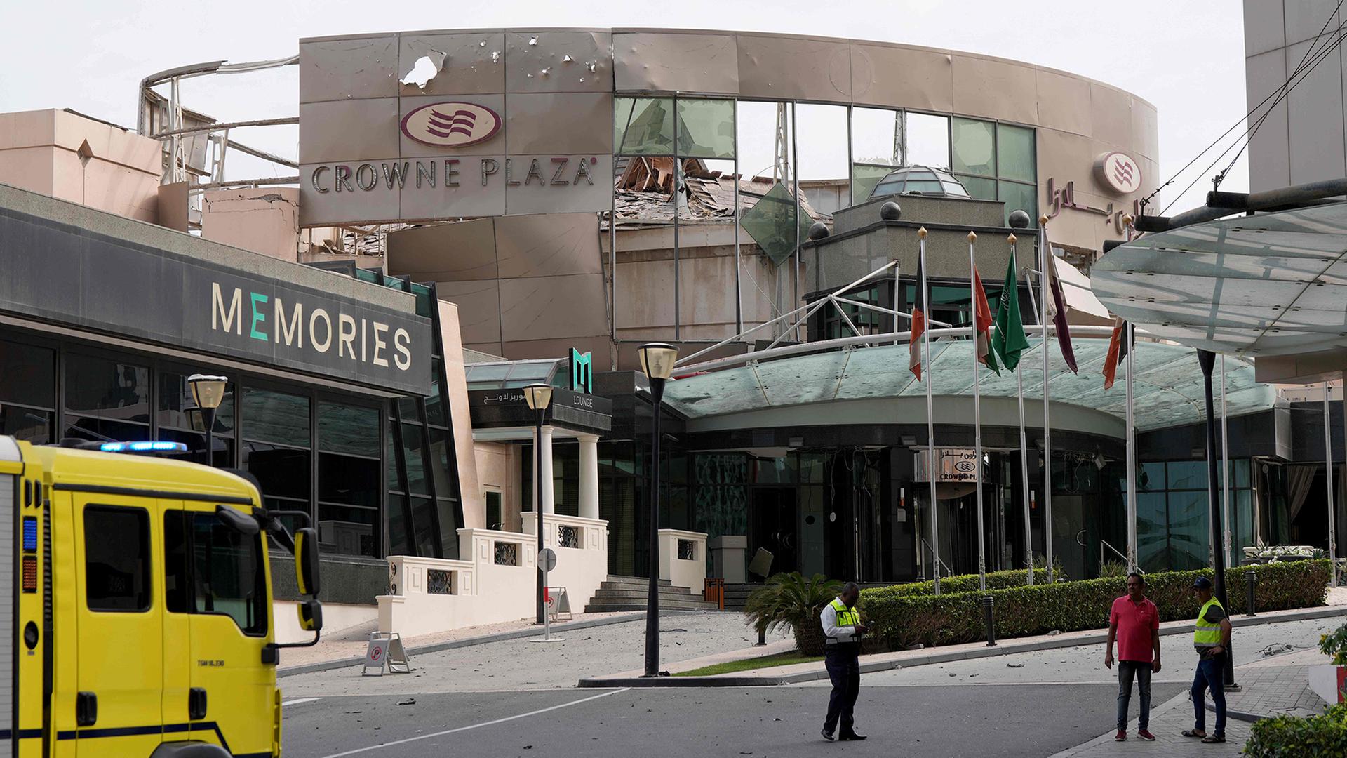 Sicherheits- und Zivilschutzkräfte stehen vor dem beschädigten Crown Plaza Hotel in Manama. | AFP