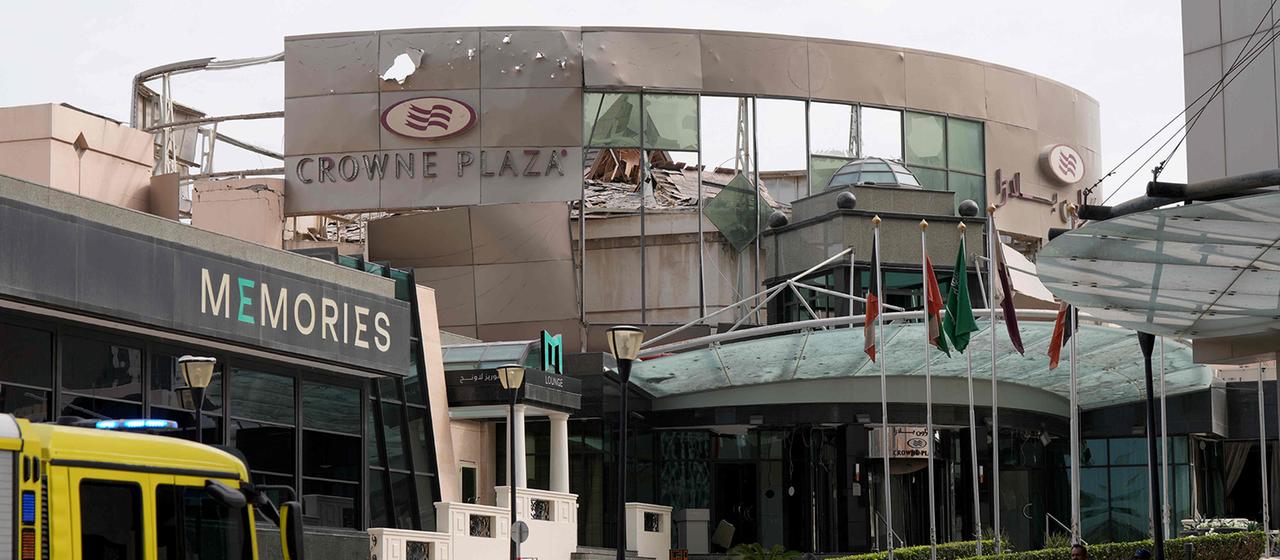 Sicherheits- und Zivilschutzkräfte stehen vor dem beschädigten Crown Plaza Hotel in Manama.