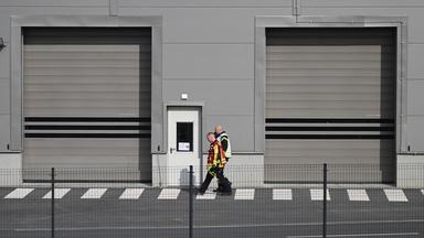 Mitarbeiter der Feuerwehr gehen auf dem Gelände der Tesla-Autofabrik in Grünheide, wo die Produktion wegen eines Stromausfalls stillsteht.