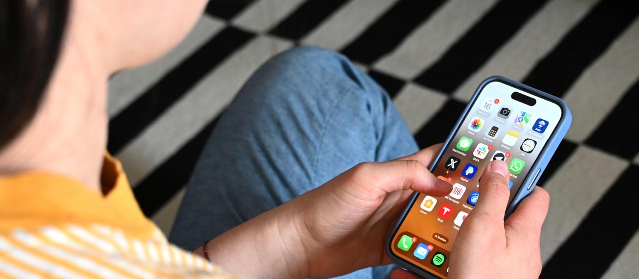 Ein Teenager sitzt auf dem Boden und benutzt ein Smartphone