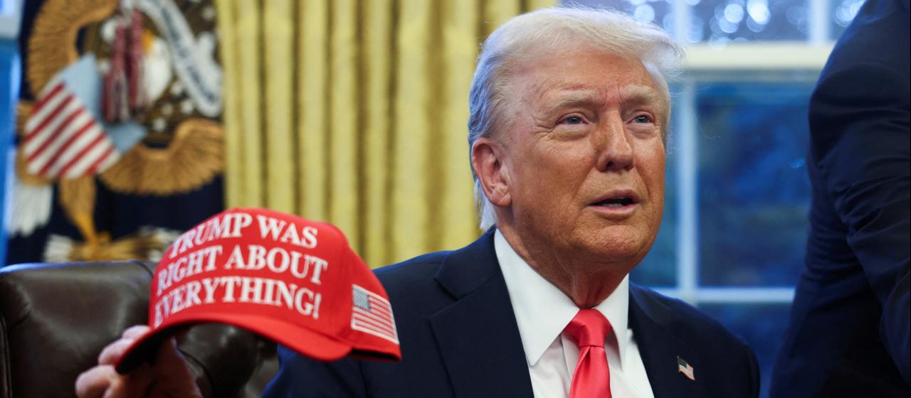 Donald Trump hält eine rote Kappe mit der Aufschrift "Trump hatte mit allem recht".