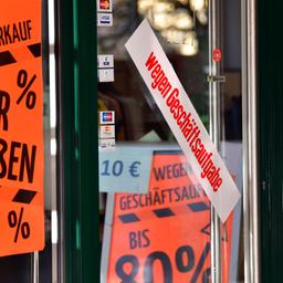 An einem Geschäft hängen Schilder mit Hinweisen auf eine nahende Schließung und Rabatte.