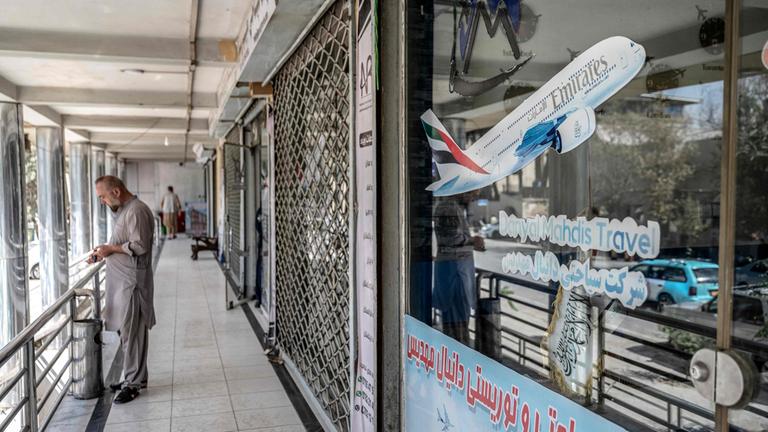 Ein Mann in Kabul vor einem geschlossenen Reisebüro