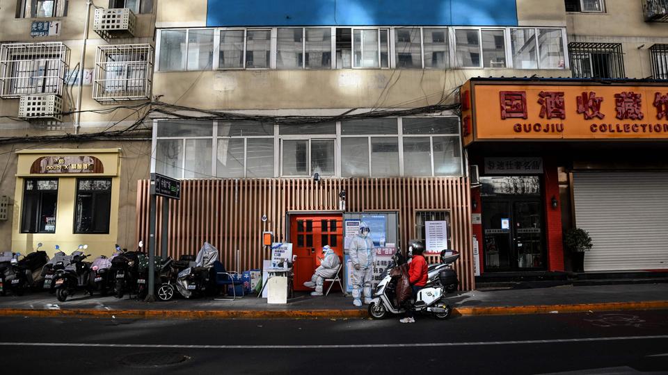 In Schutzanzüge gekleidete Sicherheitskräfte bewachen den Eingang zu einem Wohnhaus in Peking, das die Bewohner wegen des Lockdowns nicht verlassen dürfen.