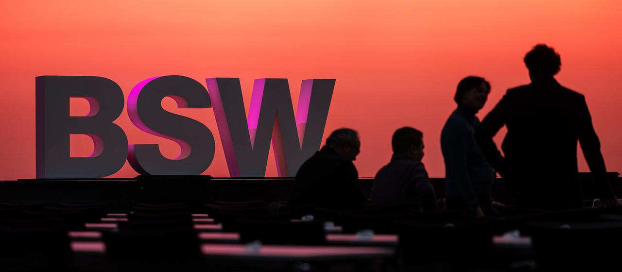 Menschen stehen vor einem BSW Schriftzug in Bonn.