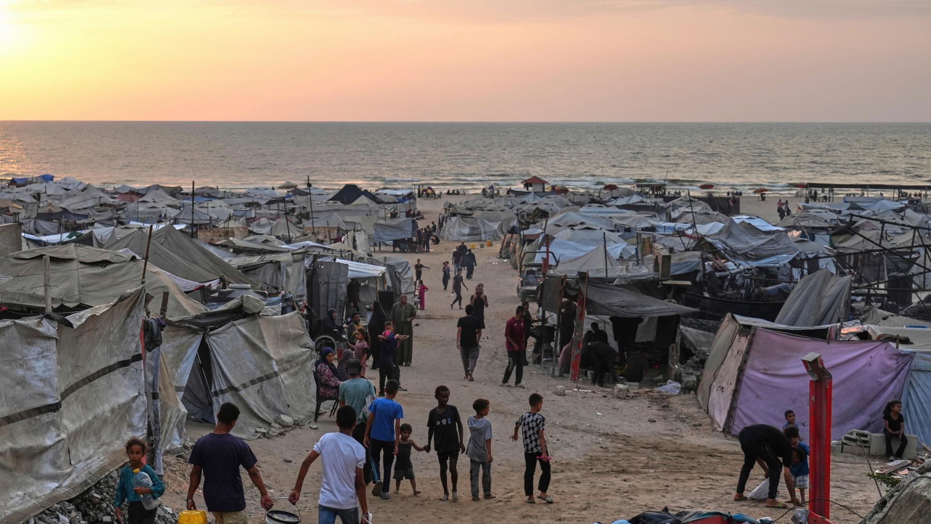 Vertriebene Palästinenser gehen durch ein behelfsmäßiges Lager am Strand von Gaza-Stadt | dpa