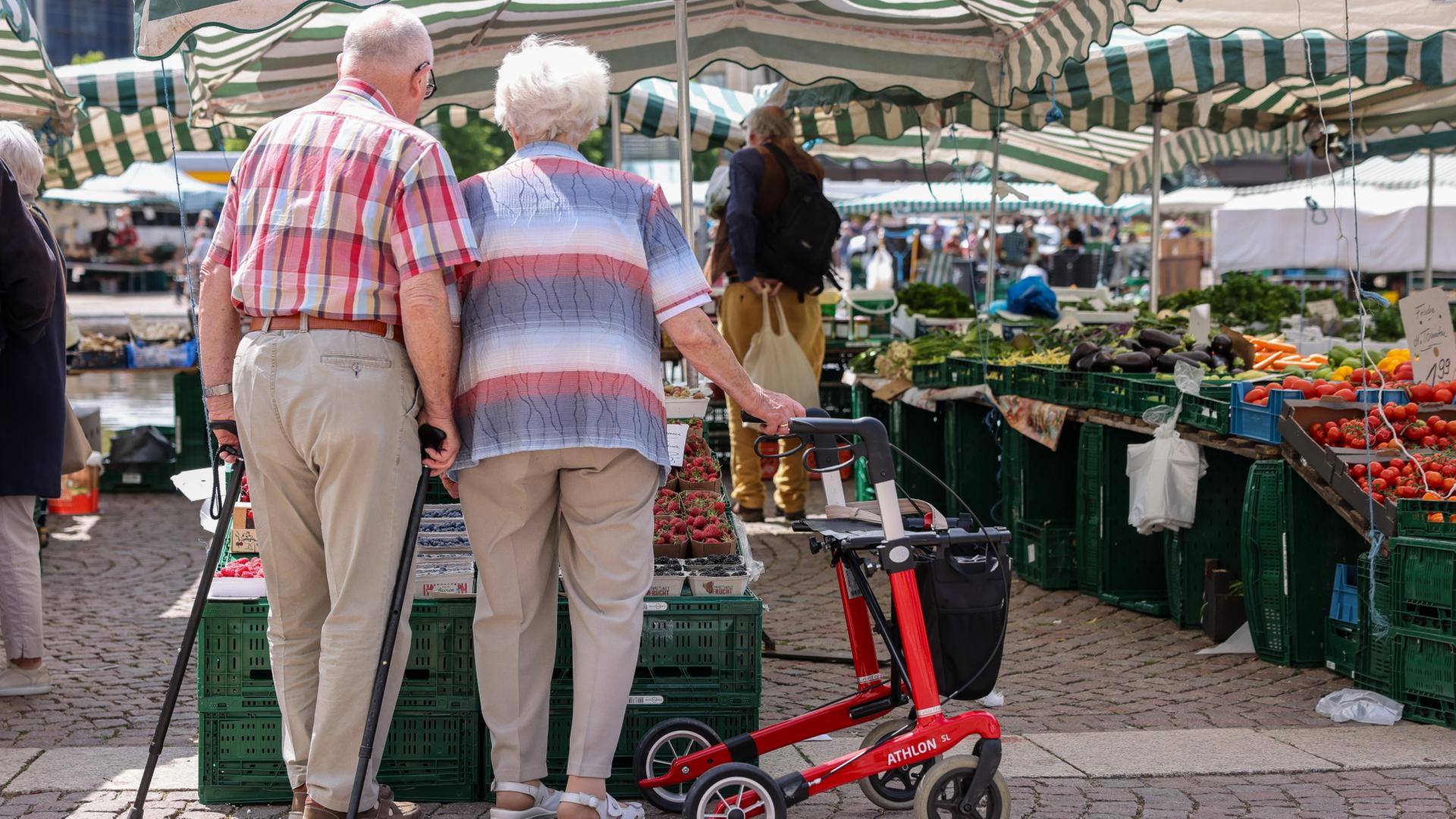 Zwei Senioren stehen mit Gehhilfen und Rollator auf dem Wochenmarkt in der Leipziger Innenstadt.  | dpa