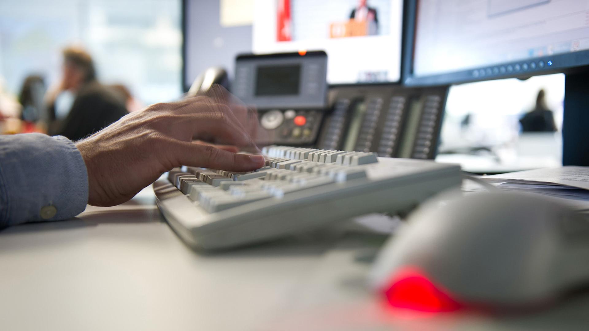 Ein Mann tippt einem Büro auf einer Tastatur.