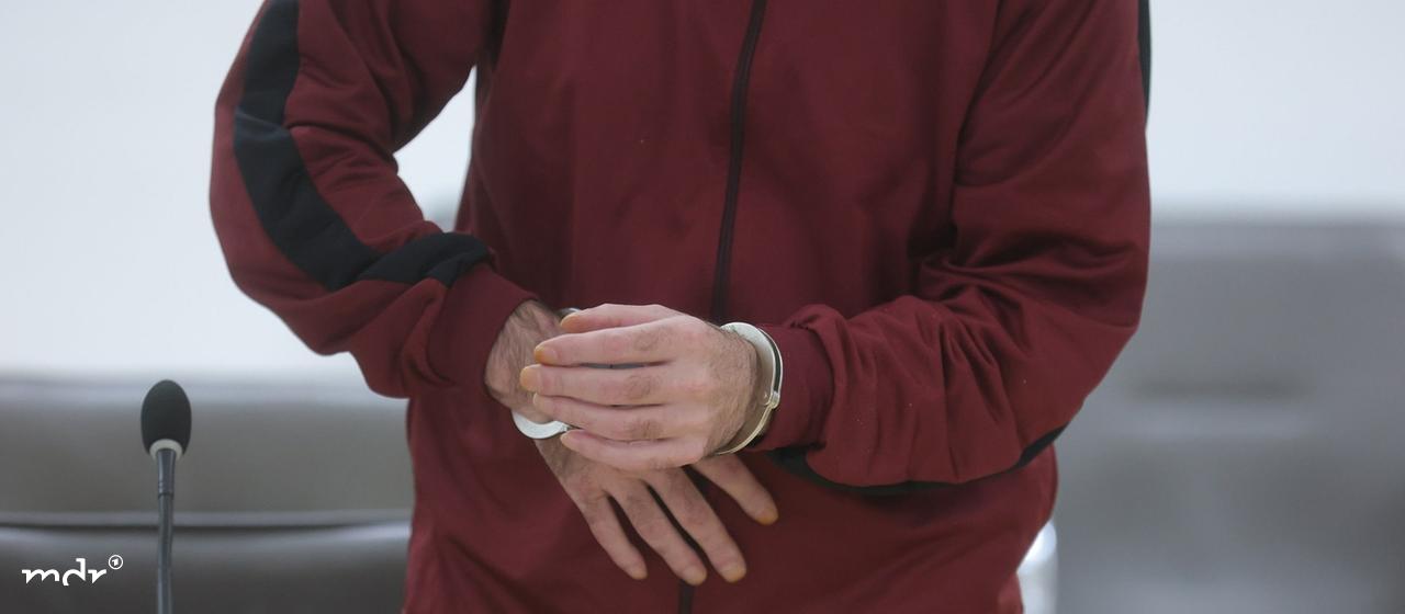 Der Angeklagte steht mit Handschellen im Gerichtssaal.