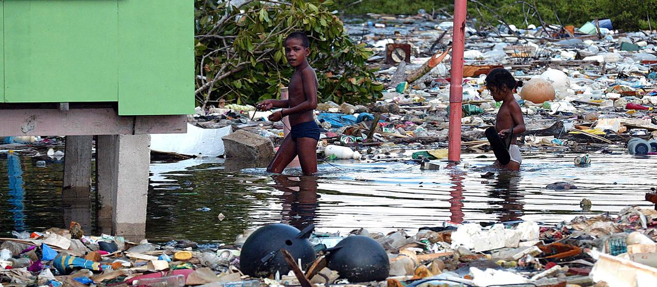 Kinder auf einem Pazifik-Atoll waten durch Müll und Wasser. | AFP Kinder auf einem Pazifik-Atoll waten durch Müll und Wasser.