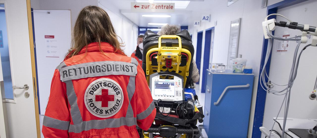 Eine Notfallsanitäterin schiebt eine Patientin auf einer Trage.
