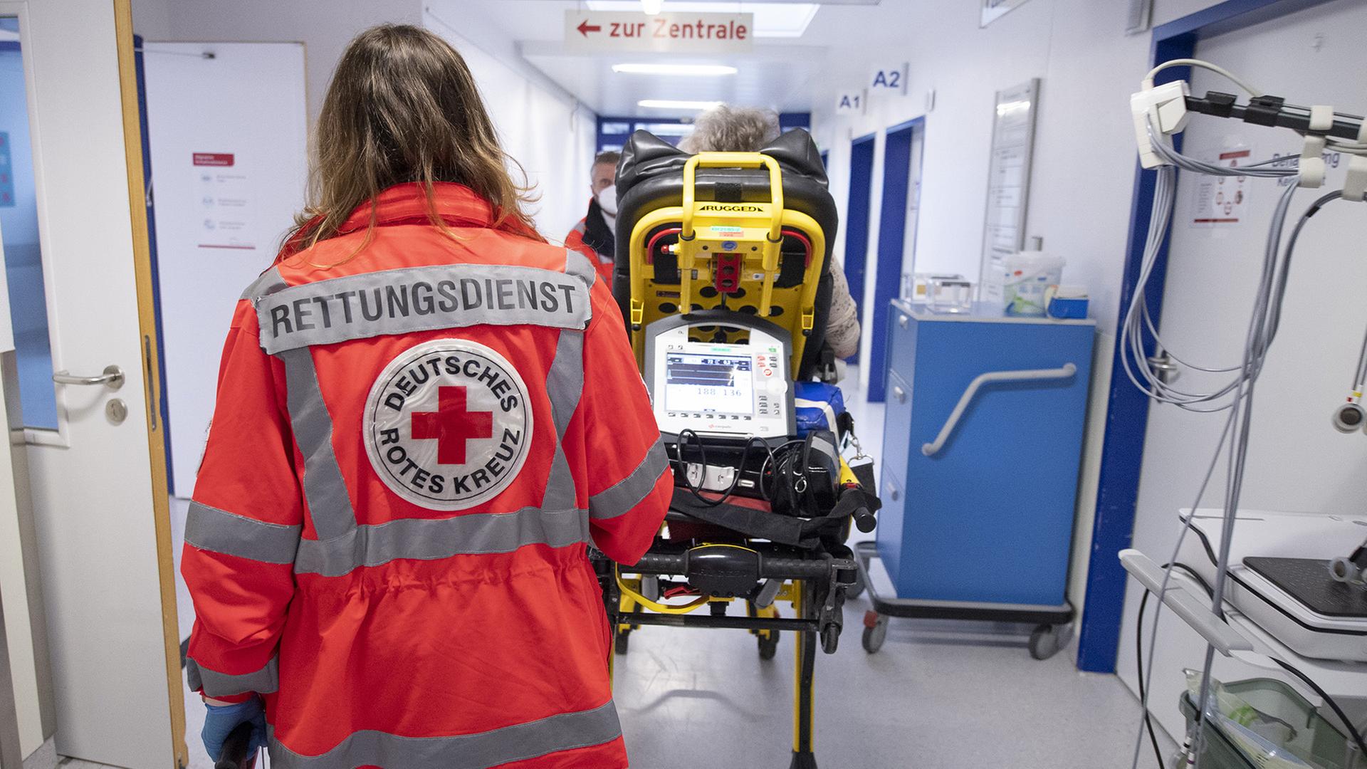 Eine Notfallsanitäterin schiebt eine Patientin auf einer Trage. | dpa