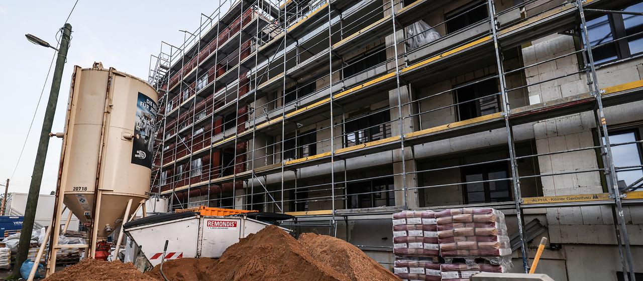 Ein Gerüst steht am Rohbau eines Wohnhauses. 
