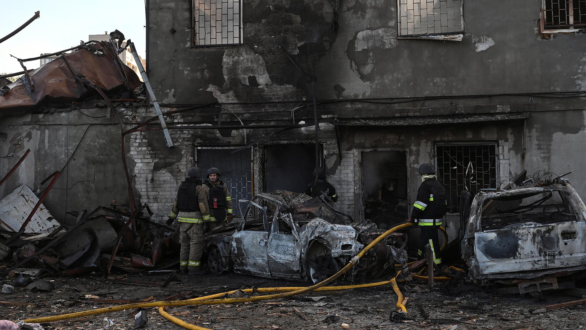 Feuerwehrleute vor einem beschädigten Haus in Saporischschja, Ukraine.  | REUTERS
