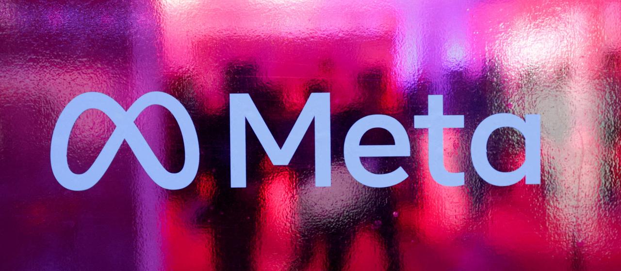 Menschen sind hinter dem Logo des Meta-Konzerns zu sehen