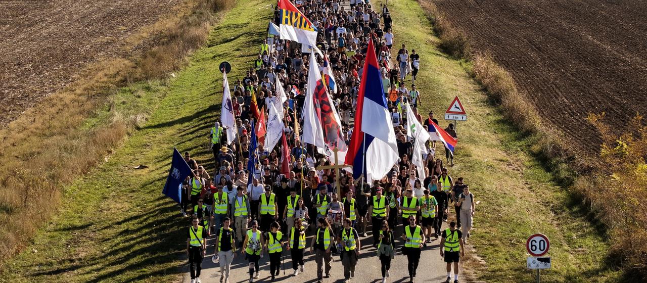 Ein Zug von Demonstrierenden läuft mit Flaggen an Feldern vorbei | AP Ein Zug von Demonstrierenden läuft mit Flaggen an Feldern vorbei